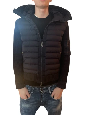 Svart dunväst från Moncler - Snygg svart dunväst från Moncler med stickade ärmar och huva. Västen har dragkedja framtill, ribbade muddar och en ficka med Moncler-logga på ärmen. Perfekt för lager-på-lager och ger en sportig look.