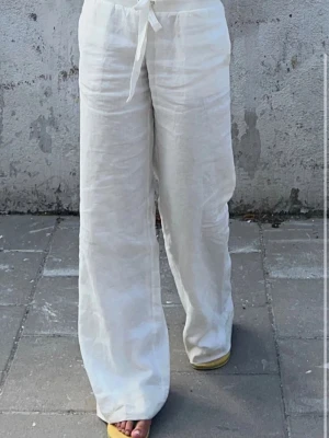 Lågmidjade linnebyxor - Säljer ett par vita linnebyxor med avslappnad passform och lågmidjade. Byxorna har raka, vida ben och är tillverkade i ett luftigt linnematerial som passar perfekt till sommaren. Ny pris är 799.