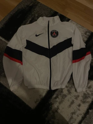 Vit PSG x Nike vindjacka - Snygg vit vindjacka från Nike i samarbete med PSG. Regnjacka för träning.Jätte bra kvalite och har bara använt två gånger för att jag spelar inte fotboll längre.Pris kan diskuteras 