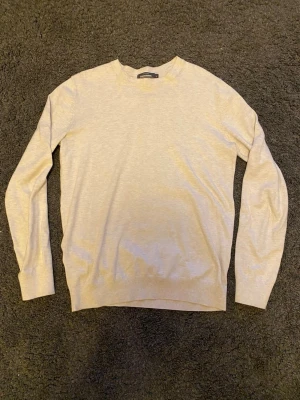 Beige tröja från Dressmann - Superskön beige tröja från Dressmann i mjuk Supima-bomull. Enkel design med rund halsringning och långa ärmar. Perfekt för dig som gillar stilrena och bekväma plagg.