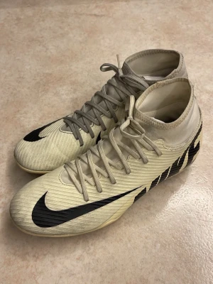  Fotbollsskor Nike  - Säljer ett par snygga fotbollsskor från Nike. Skorna har snörning och är tillverkade i syntetmaterial med dobbar för bra grepp på planen. Perfekta för dig som vill ha stilrena och funktionella skor till fotbollen. 