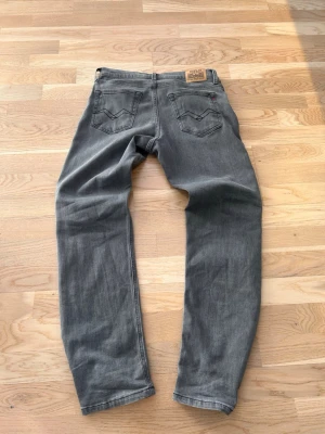 Grå raka jeans från Replay - Säljer ett par grå jeans från Replay med raka ben och klassiska bakfickor med V-formad söm. Jeansen har en avslappnad passform och är tillverkade i mjukt denimtyg. Perfekta för en chill och stilren look.