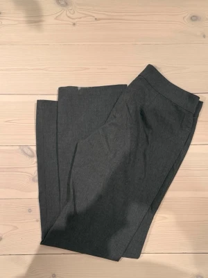 Mörkgrå kostymbyxor med rak passform - Snygga mörkgrå kostymbyxor med rak passform med en låg midja. Byxorna har andvända vilket syns, finns tecken på slitning. Sköna och fina utöver det💕