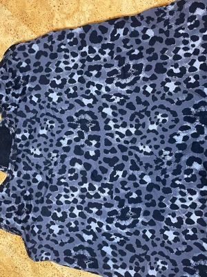 Leopardmönstrad topp i blått och svart - Snygg topp med leopardmönster i blå och svarta toner. Toppen har rund halsringning och är ärmlös, perfekt för en trendig och edgy look. Materialet känns lätt och andas, vilket gör den skön att bära hela dagen.