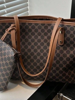 Brun shoppingväska från Shein - Snygg shoppingväska från Shein brunt konstläder med klassiskt Triomphe-mönster. Väskan har långa handtag i ljusbrunt läder och en rymlig, rektangulär form. 