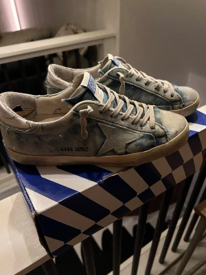 Blå golden goose Superstar sneakers - Tja säljer ett par riktigt unika golden goose. De finns lite defekter på sulan misstänker att förra ägaren kan ha limmat sulan på vissa ställen inte helt säker men annars ganska bra skick. Box och dustbag medföljer 