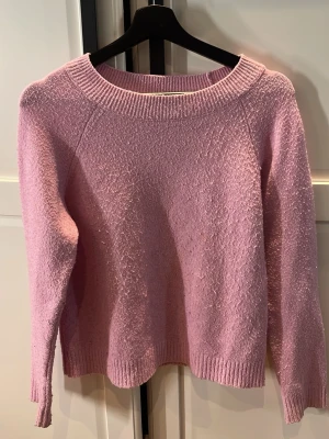 Rosa vero Moda tröja - Söt ljusrosa stickad tröja från Vero Moda med rund halsringning och ribbade muddar. Tröjan har en mjuk struktur och är perfekt för lager-på-lager. Enkel och stilren design som passar till många outfits. Den är dock rätt så nopprig 