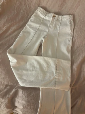 Vita linnebyxor med pressveck - Snygga vita linnebyxor med raka ben och markerade pressveck framtill. Byxorna har hög midja, knapp och dragkedja samt fickor i sidorna. Perfekta för en fräsch och stilren look. Materialet är luftigt linne som passar bra till varmare dagar.