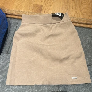 Beige stickad kjol från Aim'n - Supersnygg beige stickad kjol från Aim'n med insydda shorts bred midjeresår och stilren design. Perfekt för dig som vill ha kjol-looken men ändå känna dig bekväm. Mjuk och stretchig kvalitet som ger en clean och modern vibe.