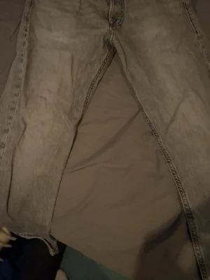 Gråa raka jeans från Jack & Jones - Snygga gråa jeans från Jack & Jones med klassisk rak passform. Jeansen har en ljus tvätt och tydliga sömmar, perfekta för en avslappnad och trendig stil. Tillverkade i slitstarkt denim-material.