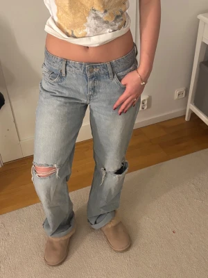 Ljusblå baggy jeans från Zara med slitningar.   - Säljer ett par ljusblå baggy jeans med slitna detaljer på båda knäna. Jeansen har fem fickor, låg midja och raka ben. Perfekta för en avslappnad och trendig look. Tillverkade i klassisk denim. Storlek 36 
