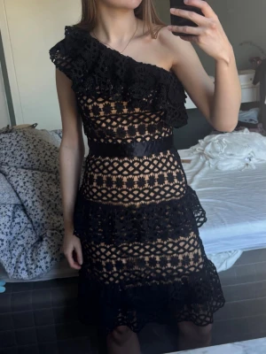 Svart spetsklänning med oneshoulder - Snygg svart klänning i spets med oneshoulder och volangdetalj. 