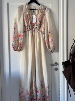Blommig långklänning med puffärm - Superfin långklänning från Neo Noir i ljus beige med blommigt mönster i rosa, gul och blå toner. Klänningen har v-ringning, långa puffärmar och ett flowy fall.  nypris 1000kr