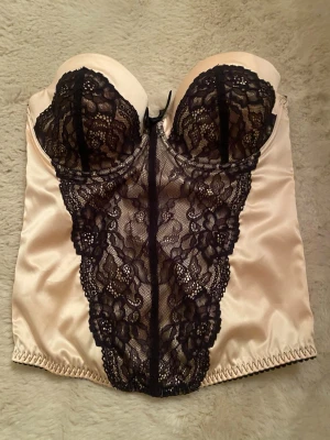  Korsett stl 75c - Snygga korsetter i champangefärgat samt röd satin med svarta spetsdetaljer. Pefekt skick. 150kr/styck