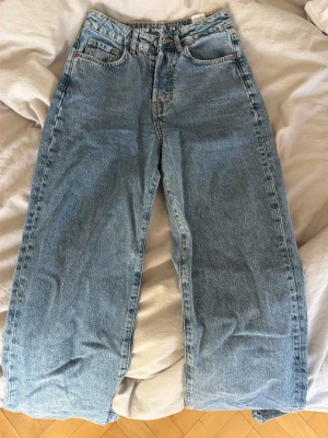 Vida jeans - Säljer ett par ljusblå jeans med regular waist och wide leg. Perfekta för dig som har långa ben. Midjan är i storlek 24 och längden 34. Använda ett fåtal gånger finns en fläck längst ner, endast tvättat som vanligt så går säkert att få bort om man försöker mer!