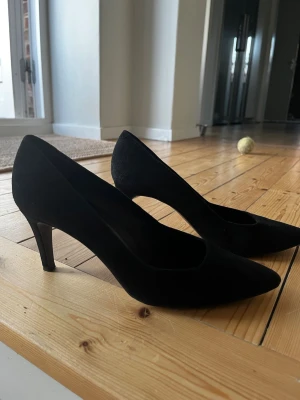 Svarta klassiska pumps i mocka från billi bi - Stilrena svarta pumps från Ellos i mjuk mocka med spetsig tå och medelhög klack. Perfekta för dig som vill ha en tidlös och elegant sko med enkel design. Passar till många olika outfits och ger en snygg siluett.
