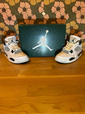 Air Jordan 4 Retro oxidized green  - Snygga Air Jordan 4 Retro sneakers i vitt läder med svarta detaljer och meshpaneler. Klassisk siluett med högt skaft och ikonisk Jumpman-logga på plösen. Perfekta för dig som vill sticka ut med stilrena och sportiga sneakers.