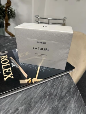 Byredo La Tulipe Eau de Parfum - Byredo La Tulipe Eau de Parfum i elegant vit kartong med subtilt mönster. Parfymen har en stilren och minimalistisk design, perfekt för dig som gillar exklusiva och moderna dofter.