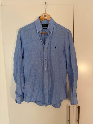 Blå linneskjorta från Polo Ralph Lauren - Klassisk blå skjorta från Polo Ralph Lauren i blått linne. Union färg och passform som gör den perfekt får kommande vår och sommar. Skjortan är i storlek XS men känns större i storleken. 