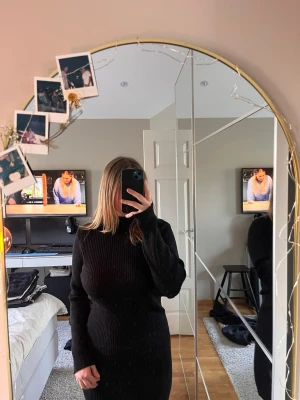 Svart ribbad poloklänning Lindex XS - Snygg svart ribbad poloklänning från Lindex i storlek XS. Klänningen har lång ärm, figurnära passform och hög polokrage. Perfekt för dig som gillar en stilren och enkel look. Materialet är stretchigt och bekvämt.