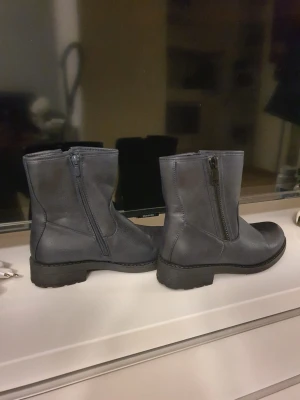 Svarta boots med dragkedja - Säljer ett par svarta boots i skinnimitation med grov sula och dragkedja på sidan. Klassisk modell som passar till många olika stilar. Sköna att gå i och perfekta för höst och vinter.