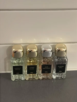 Zara parfymset med fyra dofter - Fyra eleganta parfymflaskor från Zara: Emerald Enigma, Citrine Flame, Ruby Reverent och Sapphire Spell. Flaskorna är i glas med metallfärgade lock och har olika färg på vätskan – grön, gul, rosa och blå. Perfekt för dig som vill ha variation i din doftgarderob.