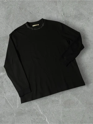Svart långärmad topp Acne Studios - Svart långärmad topp från Acne Studios med diskret logga runt halsringningen. Klassisk rak passform och mjukt material som känns skönt mot huden. Perfekt att styla med jeans eller kjol för en clean look.