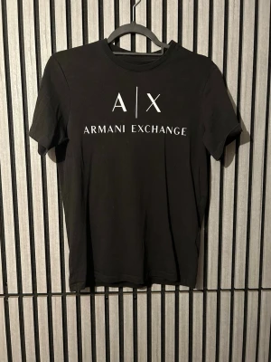 Svart Armani Exchange t-shirt - Snygg svart t-shirt från Armani Exchange med vit logga och text framtill. Använd Max 5 gånger pris kan diskuteras 