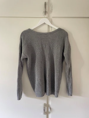Stickad tröja  - Går att använda både fram o baksida beroende vart man vill ha V-ringningen. Lös tråd på insidan men inget som syns när tröjan sitter på. 