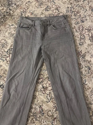 Grå raka jeans storlek 38 - Säljer ett par grå jeans med rak passform och klassisk femficksdesign. De är knappt använda och sitter snyggt.