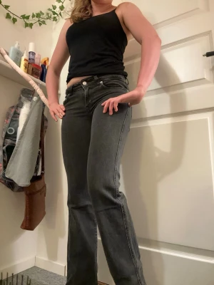 Svarta bootcut jeans med silverknappar - Snygga svarta bootcut jeans med fem fickor och silverfärgade knappar. Jeansen har en klassisk passform med lätt utsvängda ben och normal midja. Perfekta till sneakers eller boots för en avslappnad look.