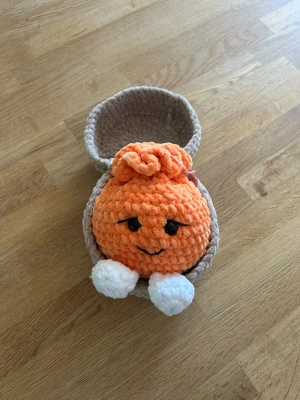 Virkad dumpling med korg - Säljer en virkad orange dumpling med korg. Perfekt som dekoration eller leksak. Allt är handgjort i mjukt garn och ögonen är säkerhetsögon.
