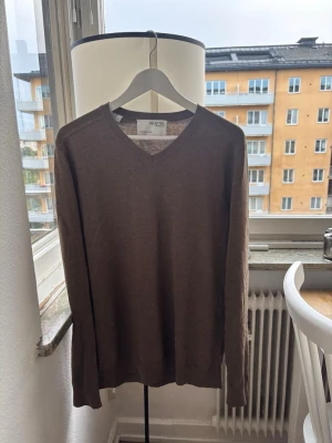 Brun V-ringad stickad tröja - Mjuk och stilren brun stickad tröja från  Selected homme med V-ringning och långa ärmar. Perfekt för lager på lager och enkel att matcha med olika outfits. Tröjan har ribbade muddar vid ärmslut och nederkant.