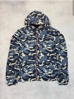 Moncler windbreaker  - Moncler Nath Camo Windbreaker  Sällsynt och exklusiv Moncler Nath vindjacka i camo. Stilren, lätt och smidig modell med huva, full zip och ikonisk Moncler-logga på ärmen.  • Storlek: M/2 • Nytt skick • Nypris ca 8 000–9 000 kr • Sällsynt modell • 100 % polyamid  Perfekt för en exklusiv streetwear-look.