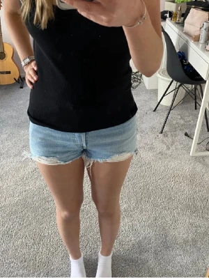 Ljusblå jeansshorts med fransig kant - Säljer ett par ljusblå jeansshorts med fransig, rå kant och klassisk femficksdesign. De är tillverkade i bomull. Perfekta för sommaren och ger en avslappnad vibe. Köpta här på Plick, Första bilden är inte min 