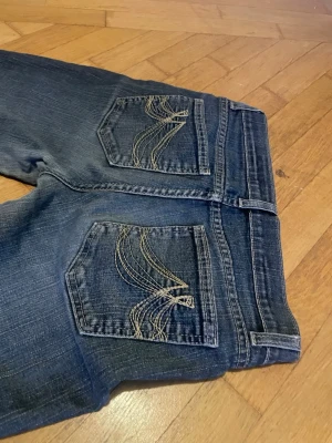 Lowrise bootcut jeans med broderade fickor - Jättesnygga blå lågmidjade bootcut jeans!! Säljer pga lite små på mig☹️skriv gärna om frågor!!💘midjemåttet är 36 rakt över!!
