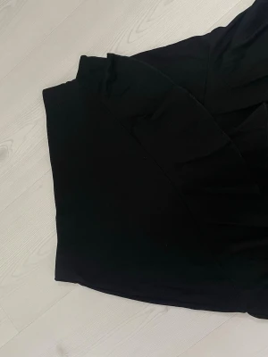 Svart omlottkjol från H&M - Svart omlottkjol från H&M i en klassisk och stilren design. Kjolen har en enkel och snygg omlott-detalj som ger en modern look. Perfekt att matcha med både sneakers och boots för en trendig outfit.