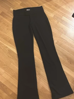 Svarta bootcut leggings från Nelly - Säljer ett par svarta leggings från Nelly i storlek S. De har en hög midja och bootcut-ben som ger en snygg siluett. Materialet är stretchigt och mjukt, perfekt för en trendig och bekväm look. Passar till många olika stilar och outfits.