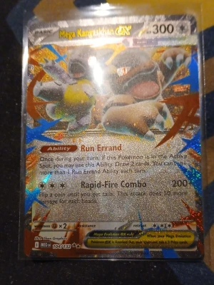 Pokémonkort Mega Kangaskhan EX - Säljer ett glittrigt Pokémonkort av Mega Kangaskhan GX med 300 HP. Kortet har färgstarka holografiska effekter och visar Mega Kangaskhan i en actionfylld pose. Text och detaljer är på engelska. Perfekt för samlare eller Pokémonfans.