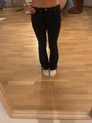 Svarta bootcut jeans med hög midja  - Säljer ett par svarta bootcut jeans med hög midja och klassiska fem fickor. Jeansen har en snygg, smal passform upptill och lätt utsvängda ben. Perfekta till en trendig vardagslook och passar till det mesta. Materialet är stretchigt denim för extra komfort. Storlek 164 på Kappahls barnavdelning men har samma storlek i dam som bär W32/34. 