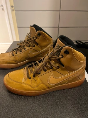 Bruna Nike high top sneakers - Skador syns på sista bilderna!!!Snygga bruna high top sneakers från Nike med klassisk swoosh på sidan. Skorna har bruna skosnören, svart vadderad insida och detaljer i både läder och textil. 