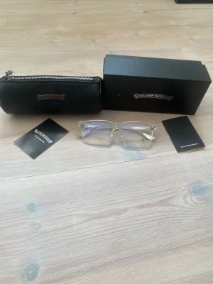 Transparenta solglasögon Chrome Hearts - Säljer ett par stilrena solglasögon från Chrome Hearts med transparent båge och silvriga detaljer på skalmarna. Glasen är ljusa med en lätt blå ton. Kommer med originalfodral och låda. Perfekt accessoar för dig som vill sticka ut.