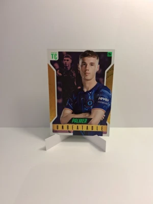 Fotbollssamlarbild Cole Palmer - Samlarbild från Panini Top Class med fotbollsspelaren Cole Palmer i Chelsea. Kortet har färgerna blå, guld, grön och svart med texten 'UNBEATABLE' och spelarstatistik på baksidan. Perfekt för dig som gillar fotboll och samlarkort.