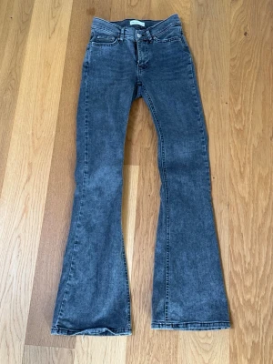 Grå bootcut jeans  - Snygga grå jeans med bootcut-modell och låg midja. Klassisk femficksdesign och dragkedja med knapp framtill. Jeansen har en lätt tvättad look och är tillverkade i ett mjukt denimtyg som ger en skön passform.