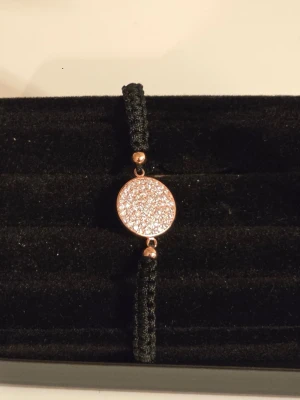 Ingnell Jewellery Josefin armband rosé svart stl L - 🖤✨ Helt nytt armband från Ingnell Jewellery, modell Josefin, i svart och rosé. Flätat svart band med rund glittrande detalj framtill och roséfärgade detaljer. Justerbar modell med dragsnöre.  🔖 Storlek: L 🎨 Färg: Svart/rosé ✨ Skick: Helt nytt och oanvänt med originaletikett kvar. 🏷️ Nypris: 299 kr  🎁 Förpackas fint i en liten presentpåse vid leverans – perfekt även som present.