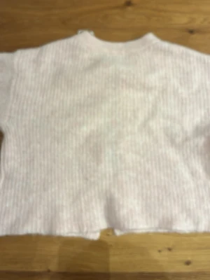 Ljusrosa stickad tröja Gina Tricot - Supersöt ljusrosa stickad tröja från Gina Tricot. Tröjan har en mjuk, fluffig känsla och ribbstickad struktur. Perfekt för dig som gillar en enkel men ändå mysig look. Rund halsringning och avslappnad passform.