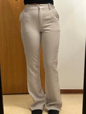 Beiga utsvängda kostymbyxor - Säljer mina beiga kostymbyxor i modellen Vilma, storlek 36  De har utsvängda ben och hög midja och är verkligen så fina för en clean och stilren look. Endast använda 1 gång och är i perfekt skick. Säljer dem bara eftersom de tyvärr är alldeles för stora för mig. Hoppas någon annan kan få användning av dem😁💕💕nypris 499kr
