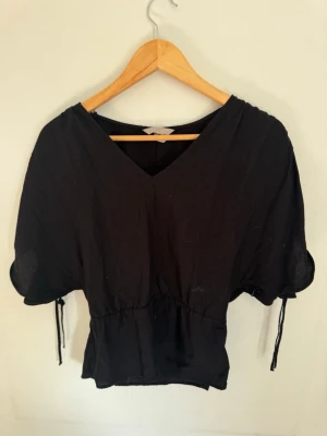 V-ringad topp H&M - Svart v-ringad topp från H&M med korta, vida ärmar och slits 💝