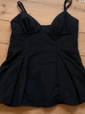 Svart linne från Zara  - Snygg svart topp med tunna axelband och markerade sömmar framtill. Toppen har en figurnära passform och lätt utsvängd nederkant. Från Zara!