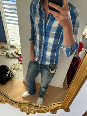 Sjukt fet skjorta från Hollister - Säljer en snygg blårutig skjorta från Hollister i storlek S. Skjortan har klassisk krage, långa ärmar och knappar framtill. Tillverkad i mjuk bomull som känns skön mot huden. Perfekt för en avslappnad och stilren look.